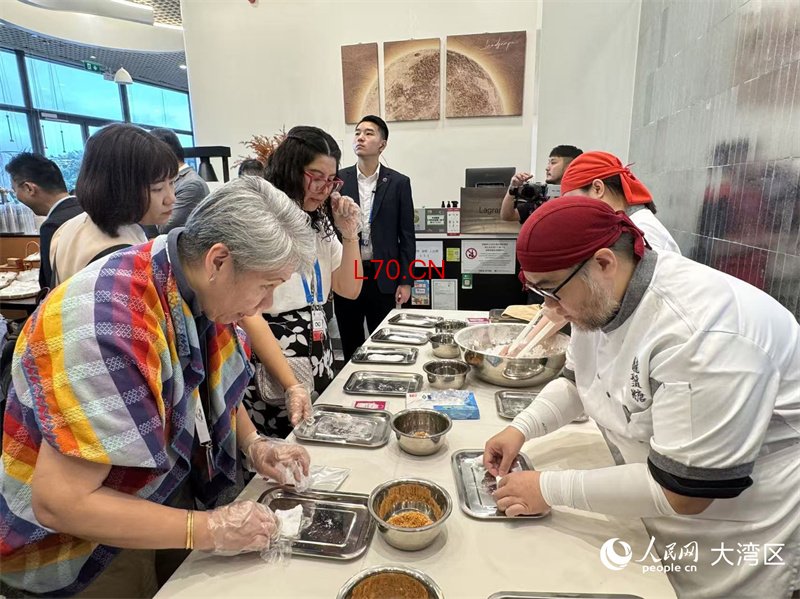 图为与会代表们被龙须糖的神奇造型深深吸引。 人民网记者 富子梅摄